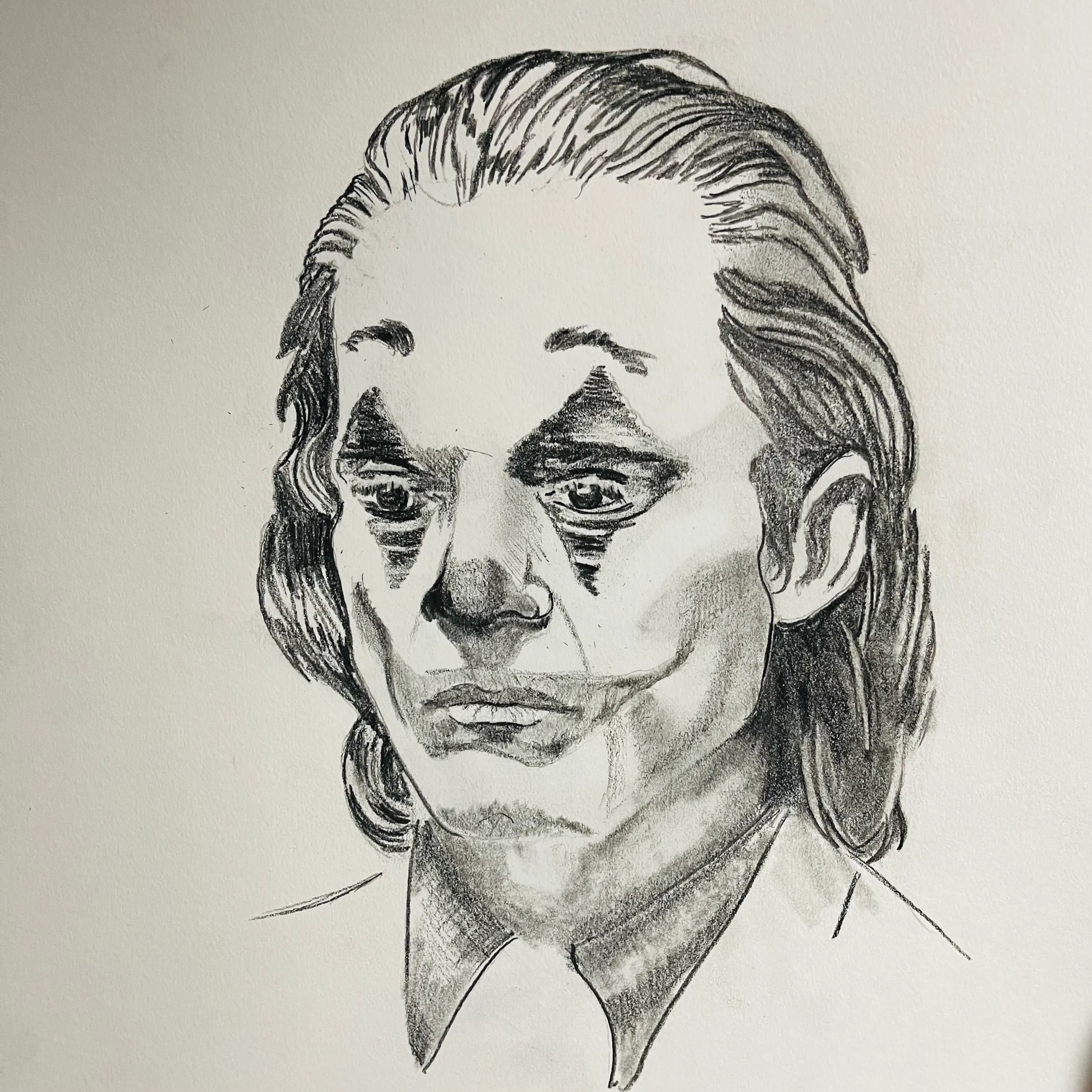 A graphite pencil portrait of a man with long hair looking downward.