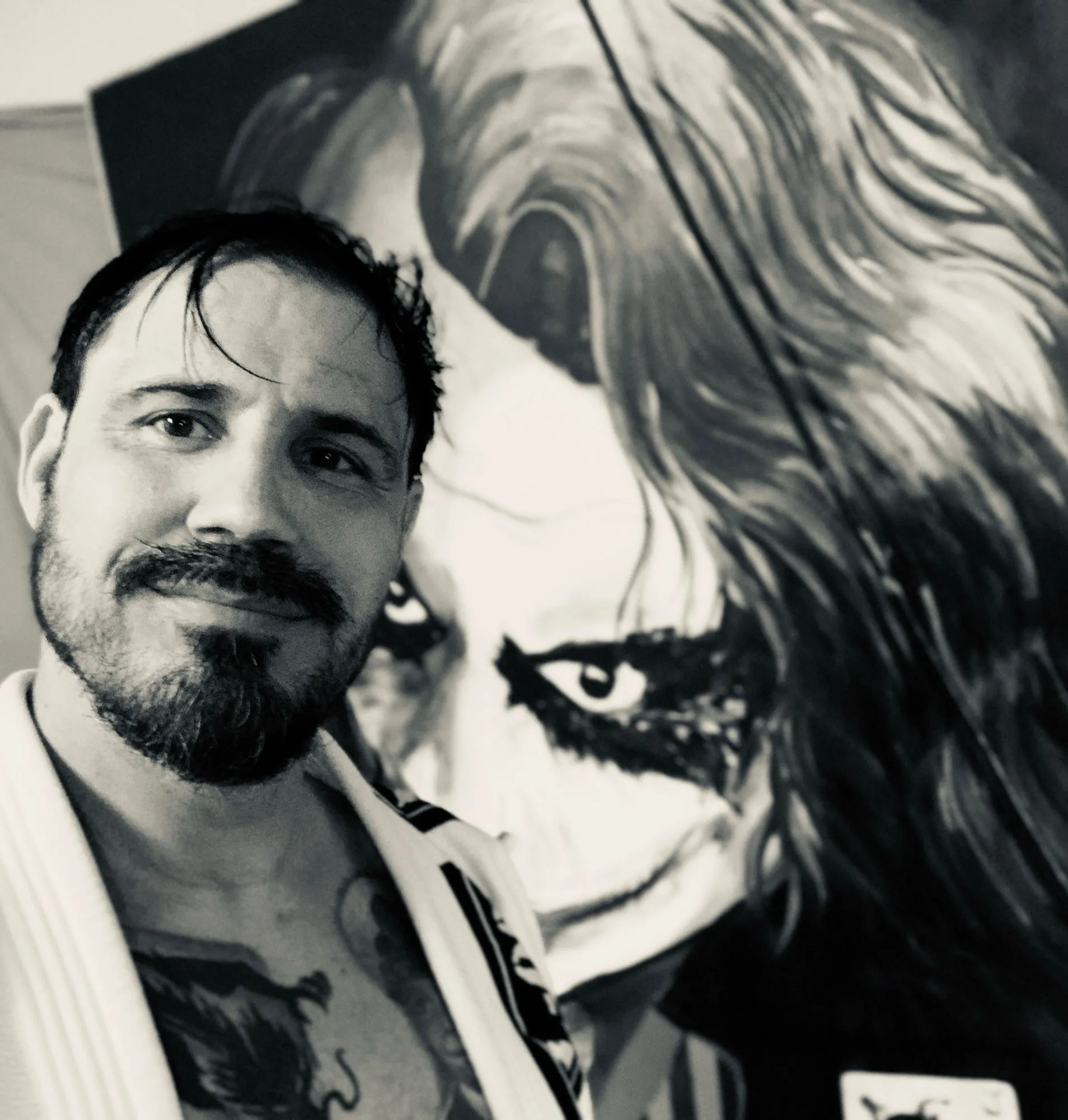 Black and white portrait of J. Orlando Santiago in front of one of his paintings.